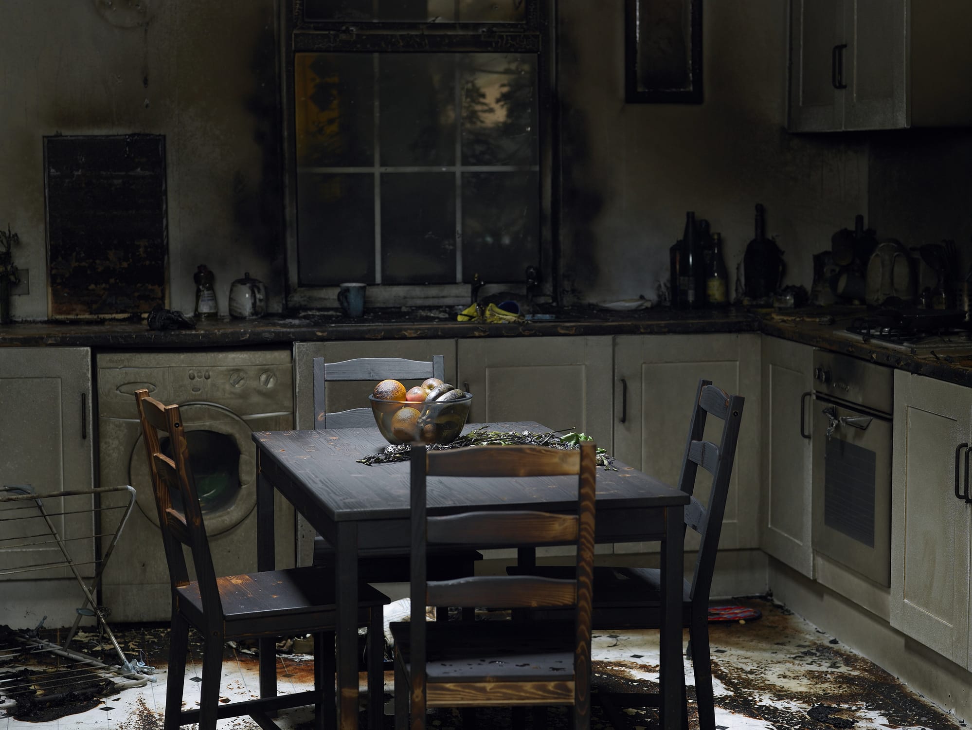 A kitchen with a dining room table damaged from a fire.