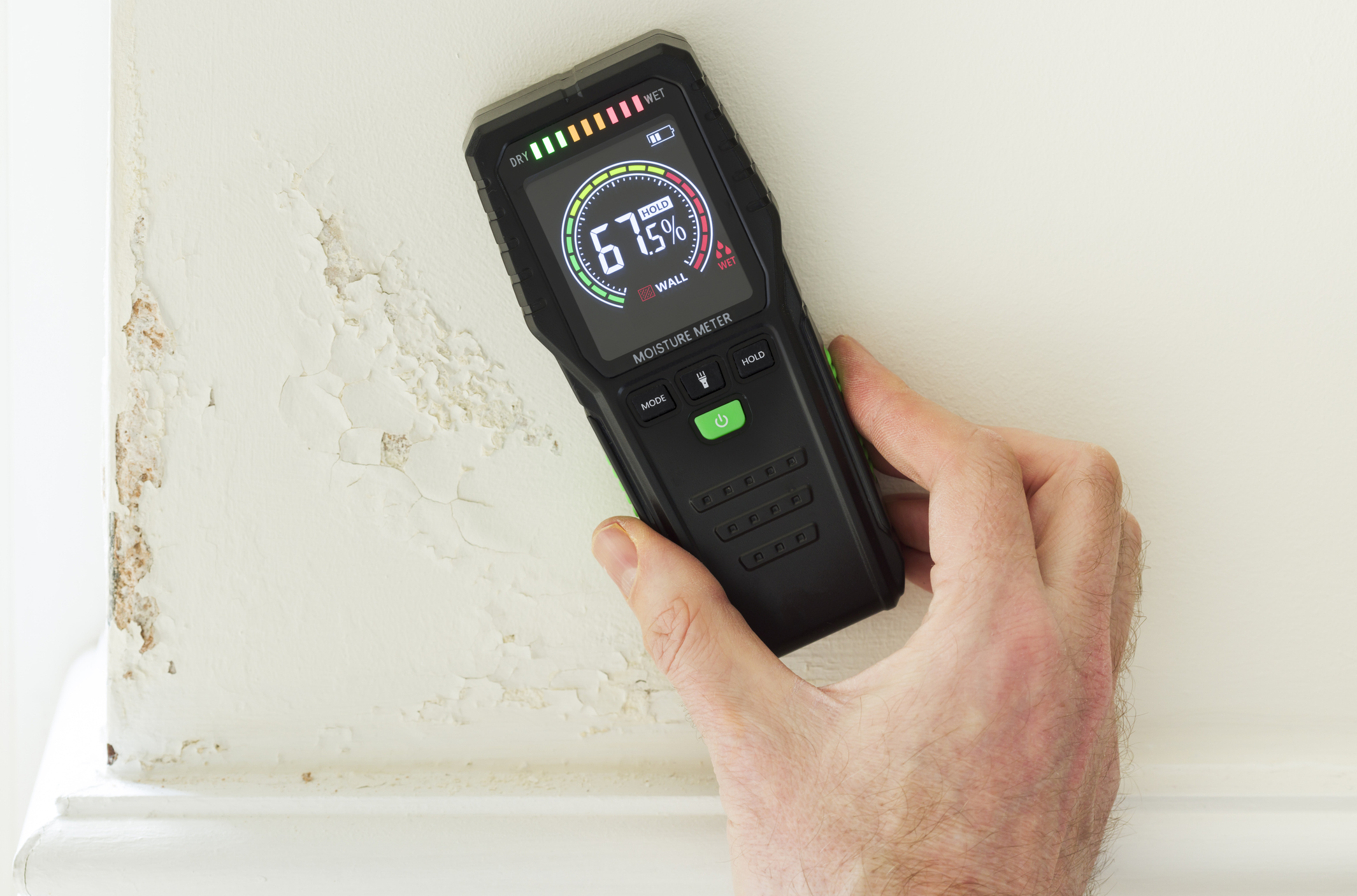 A hand molding a moisture meter to determine how far water from a leak has spread