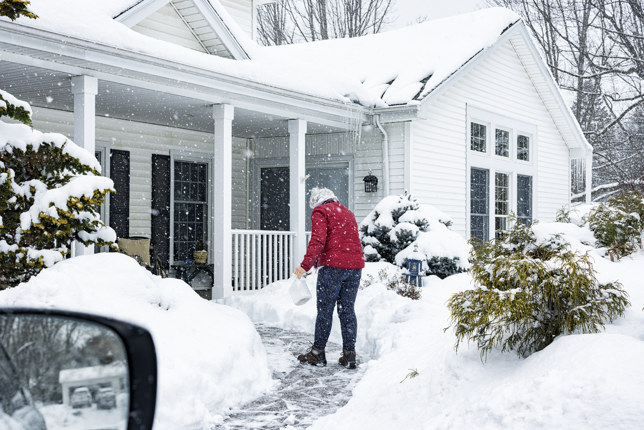 a man standing in front of a house covered in snow